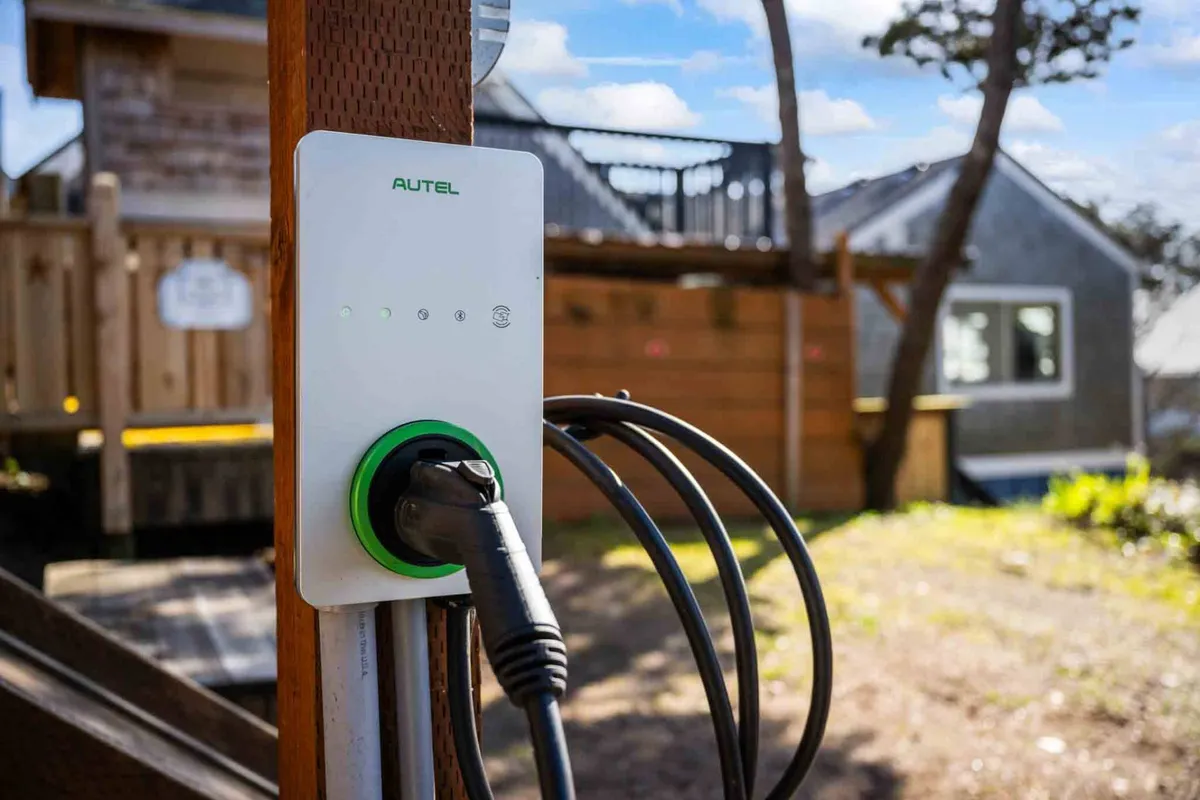 An exterior image featuring an electric vehicle charger in the driveway, set against the backdrop of the villa’s landscape. Modern amenities blend with natural surroundings, underscoring convenience for eco-conscious travelers.