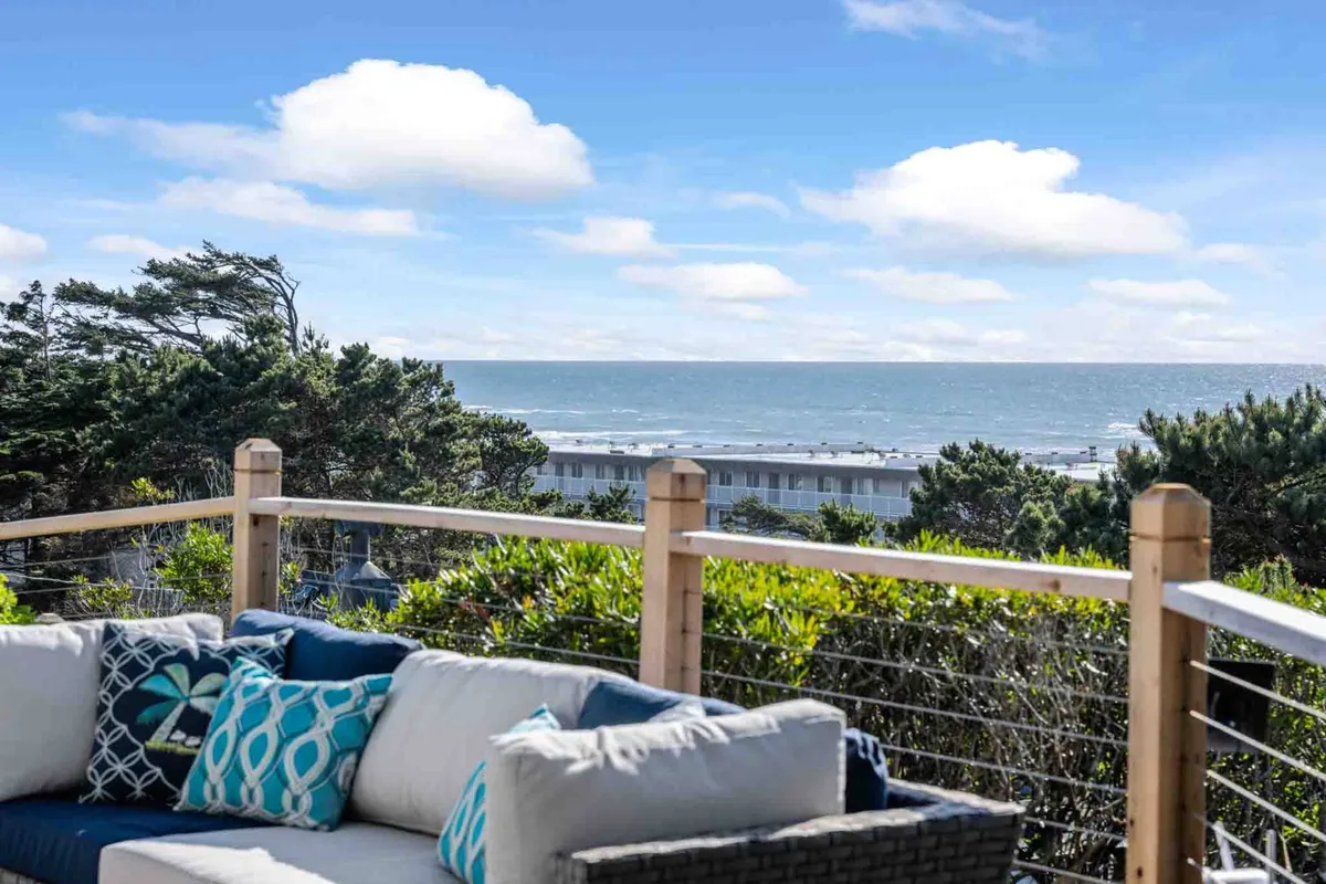 This image features a comfortable seating area positioned to overlook a stunning ocean view. The space is styled with decorative cushions and is designed for relaxation or socializing, with expansive windows bringing in natural light and offering unobstructed views of the water.