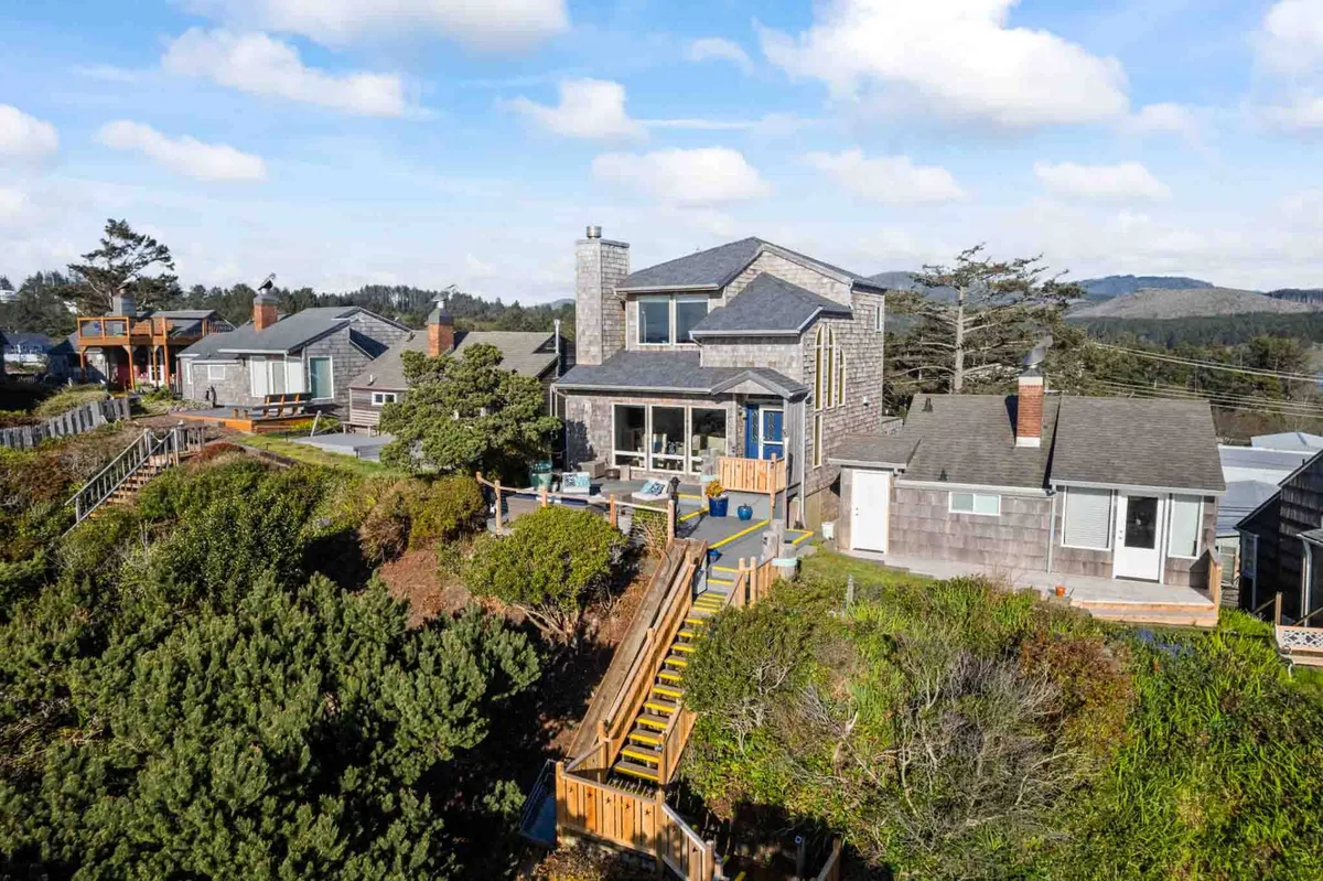 This image showcases the villa's exterior, highlighting its elevated position with large windows and a wooden staircase leading down to the surrounding greenery. The vantage point hints at panoramic views and a serene, private atmosphere, inviting guests to enjoy the outdoor deck or explore nearby trails.
